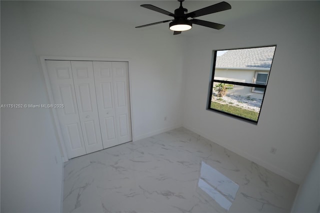 unfurnished bedroom featuring marble finish floor, ceiling fan, baseboards, and a closet