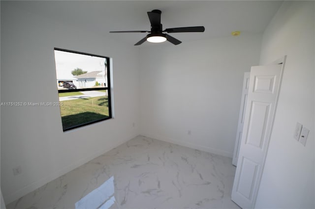 unfurnished room featuring marble finish floor, ceiling fan, and baseboards