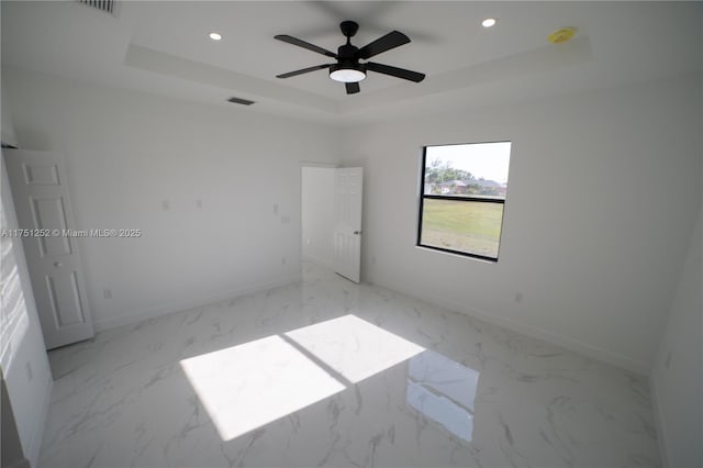 unfurnished bedroom featuring marble finish floor, baseboards, a raised ceiling, and recessed lighting