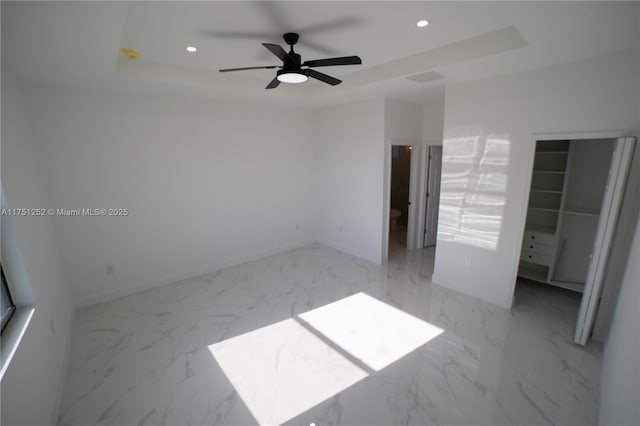 unfurnished bedroom with a tray ceiling, marble finish floor, baseboards, and recessed lighting