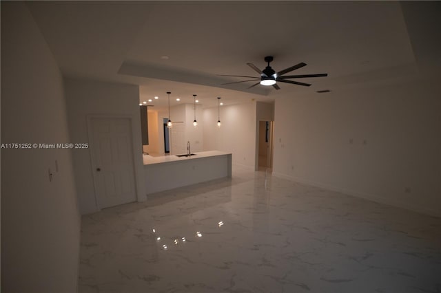 interior space with marble finish floor, baseboards, a raised ceiling, and a sink