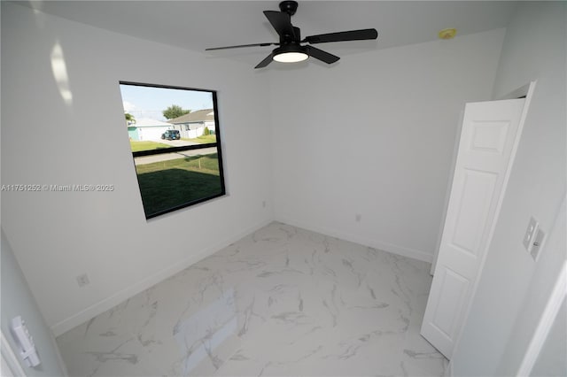 spare room with marble finish floor, ceiling fan, and baseboards