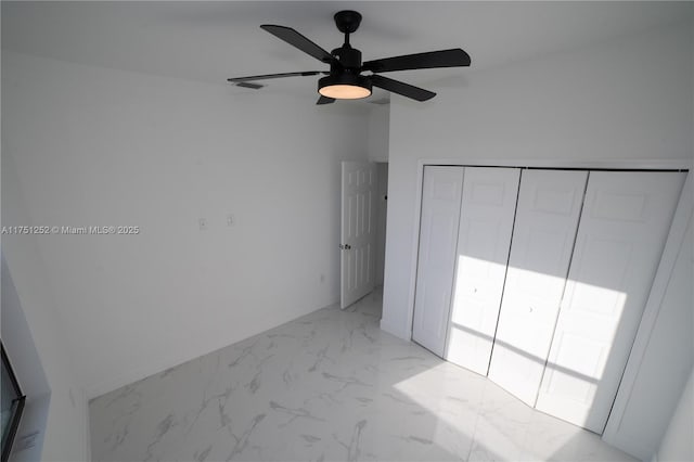 unfurnished bedroom with marble finish floor, ceiling fan, and a closet