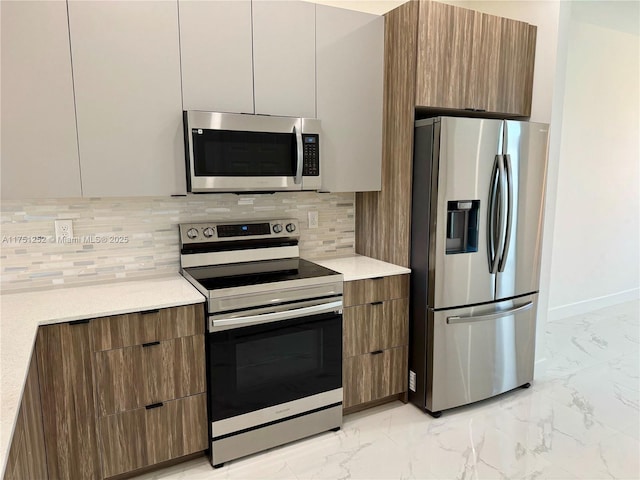 kitchen featuring brown cabinets, marble finish floor, stainless steel appliances, and light countertops