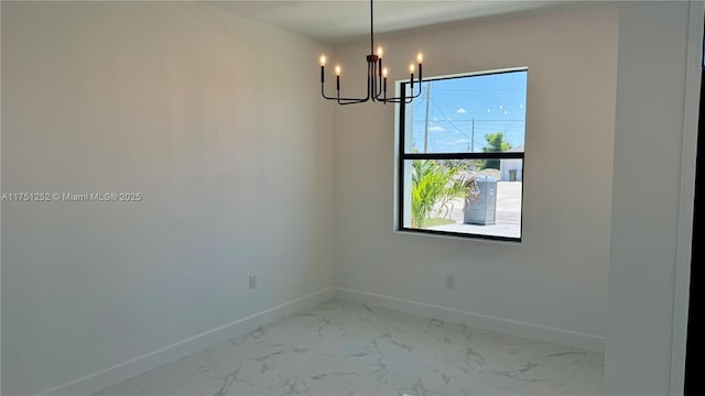 spare room with marble finish floor, baseboards, and an inviting chandelier