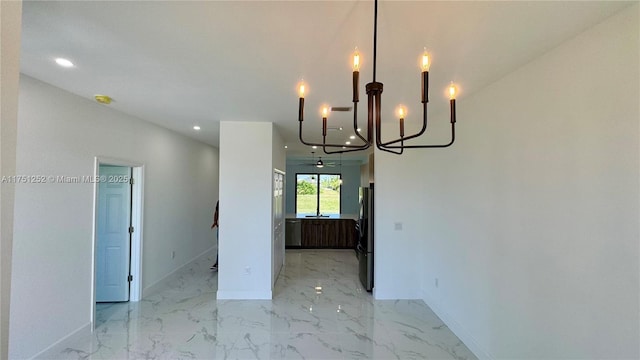 unfurnished dining area featuring a chandelier, recessed lighting, marble finish floor, and baseboards