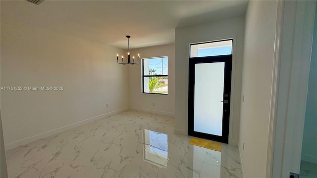 empty room with a notable chandelier, marble finish floor, and baseboards