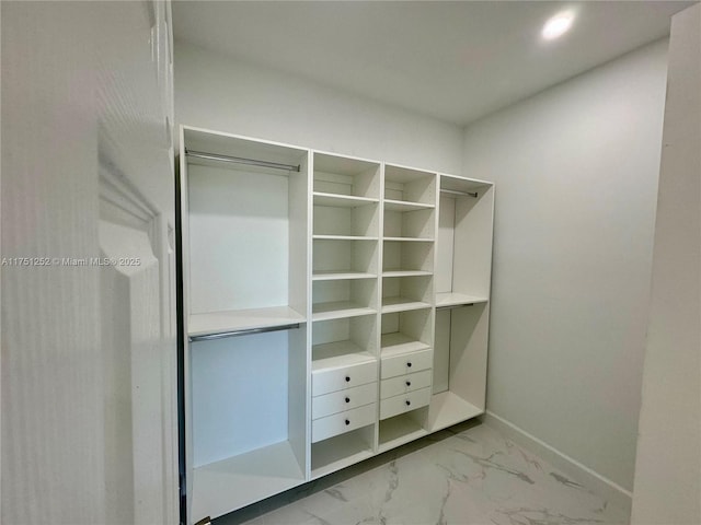 walk in closet featuring marble finish floor