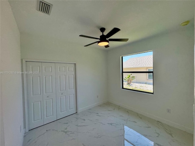 unfurnished bedroom with marble finish floor, a closet, visible vents, a textured ceiling, and baseboards