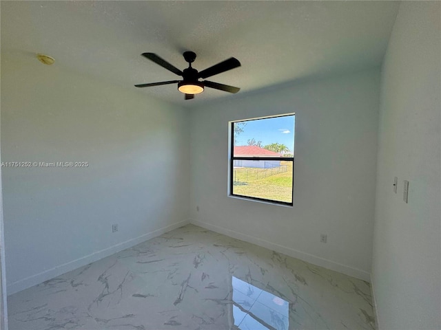 unfurnished room featuring marble finish floor, a textured ceiling, and baseboards