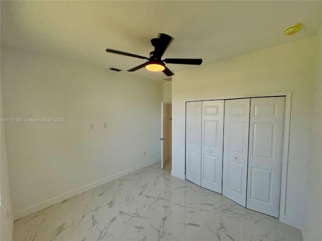 unfurnished bedroom with visible vents, baseboards, a ceiling fan, marble finish floor, and a closet