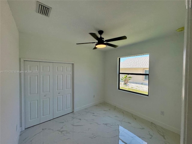 unfurnished bedroom featuring baseboards, visible vents, ceiling fan, marble finish floor, and a closet