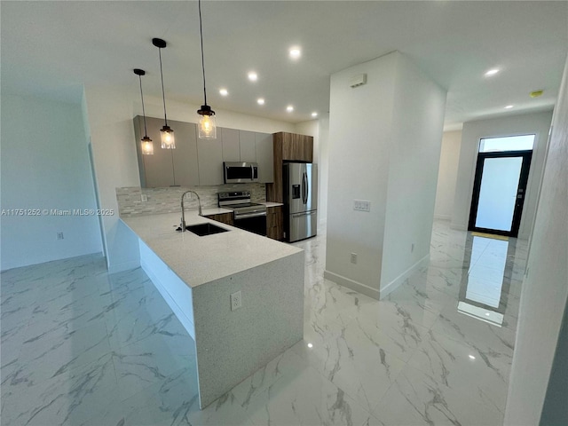 kitchen with stainless steel appliances, a peninsula, a sink, modern cabinets, and decorative light fixtures