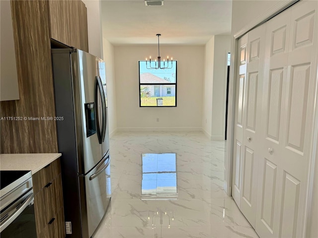 kitchen with marble finish floor, light countertops, modern cabinets, stainless steel fridge, and decorative light fixtures