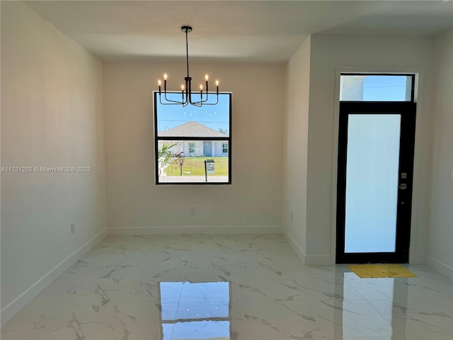 empty room with marble finish floor, an inviting chandelier, and baseboards