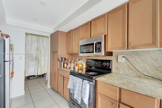 kitchen with light tile patterned floors, tasteful backsplash, light stone counters, and stainless steel appliances