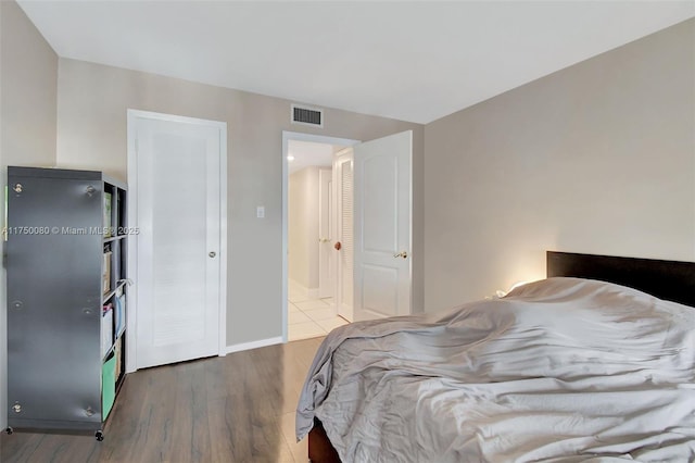 bedroom with wood finished floors, visible vents, and baseboards