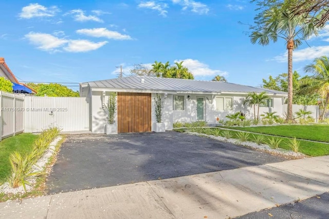 view of front facade featuring a gate, fence, metal roof, and a front yard