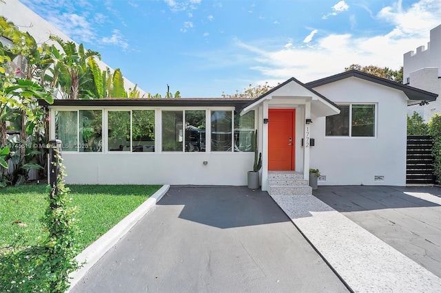 view of front of property with crawl space, stucco siding, a front lawn, and a sunroom