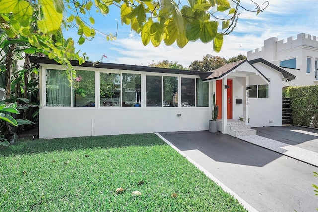 view of front of house featuring stucco siding and a front lawn