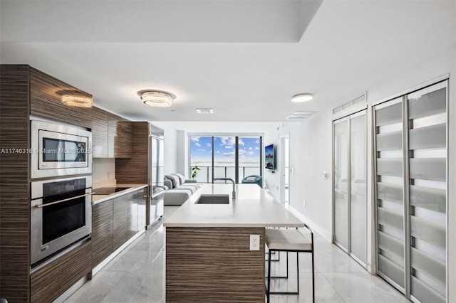 kitchen with light countertops, a kitchen breakfast bar, modern cabinets, and stainless steel appliances