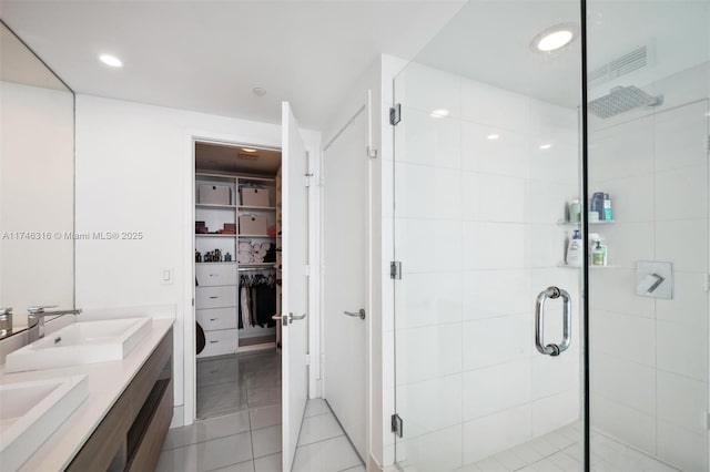 bathroom featuring a sink, a walk in closet, double vanity, and a shower stall