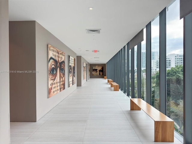 corridor with visible vents, light tile patterned flooring, and expansive windows