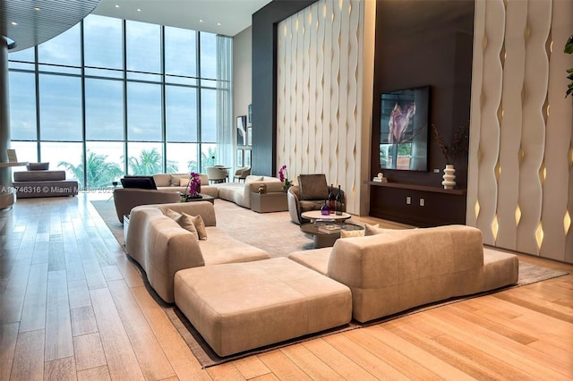 living room featuring floor to ceiling windows, wood finished floors, and a towering ceiling