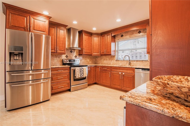 kitchen with stainless steel appliances, brown cabinetry, a sink, light stone countertops, and wall chimney exhaust hood