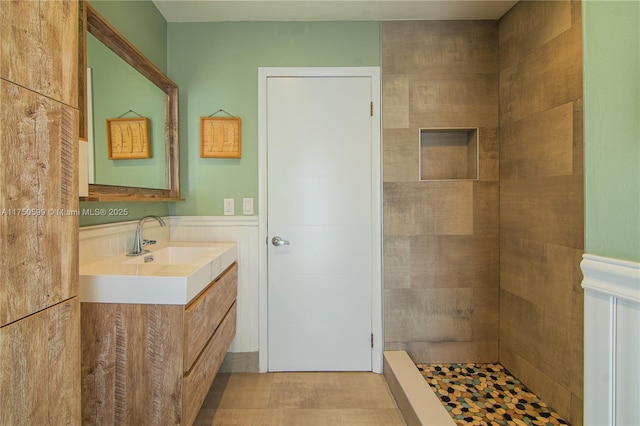 full bath with wainscoting, a shower stall, and vanity