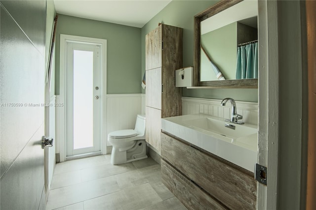 full bath featuring a wainscoted wall, vanity, and toilet