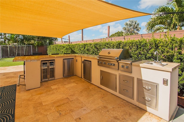 view of patio with beverage cooler, area for grilling, and fence