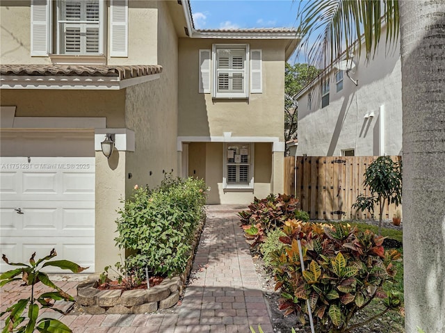 doorway to property with a tiled roof, fence, and stucco siding