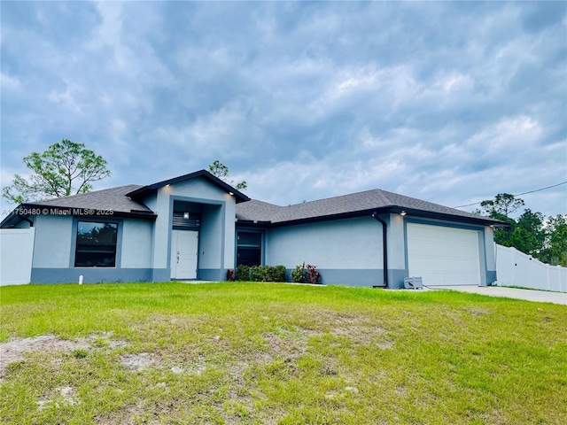 view of front facade featuring a garage, a front yard, fence, and stucco siding