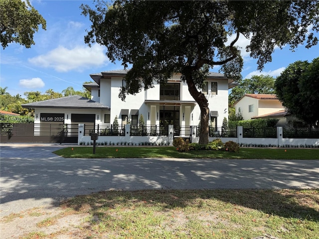 view of front of house with aphalt driveway, stucco siding, a garage, and a fenced front yard