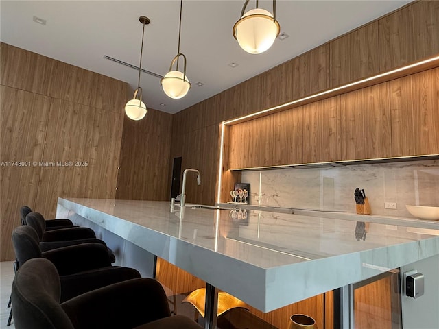kitchen featuring a kitchen breakfast bar, decorative light fixtures, brown cabinets, modern cabinets, and a sink