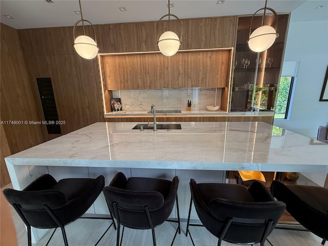 kitchen with brown cabinetry, decorative light fixtures, modern cabinets, and a spacious island