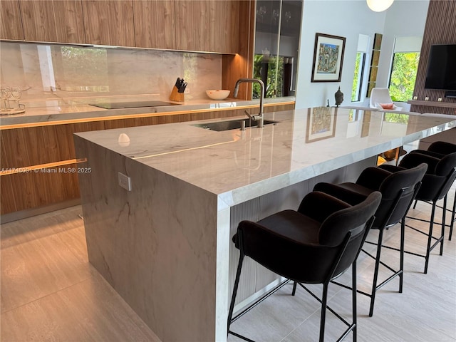 kitchen featuring a sink, decorative backsplash, black electric stovetop, and modern cabinets