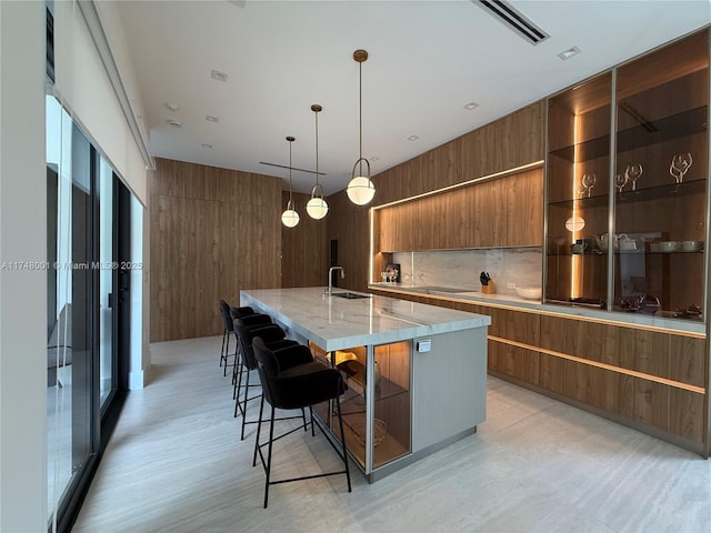 kitchen featuring a sink, a large island with sink, modern cabinets, and brown cabinetry