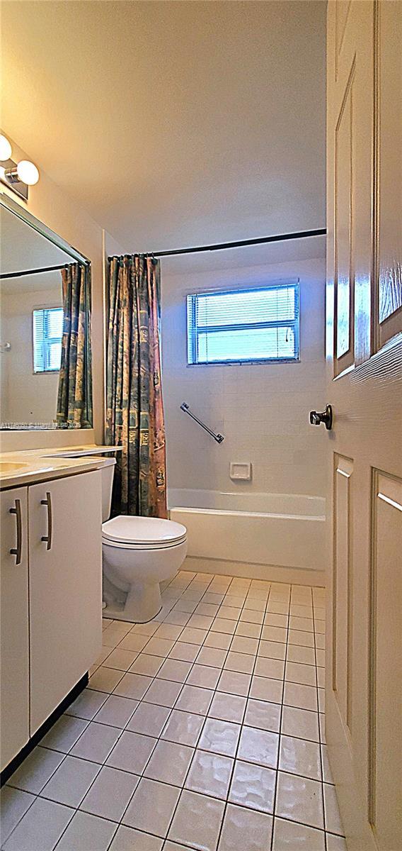 full bath with toilet, tile patterned flooring, shower / bath combo, and vanity