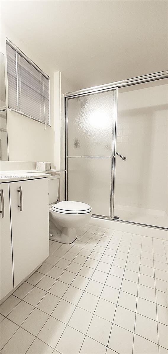 full bathroom featuring a stall shower, vanity, toilet, and tile patterned floors