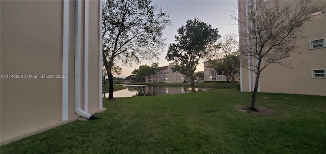 yard at dusk featuring a water view