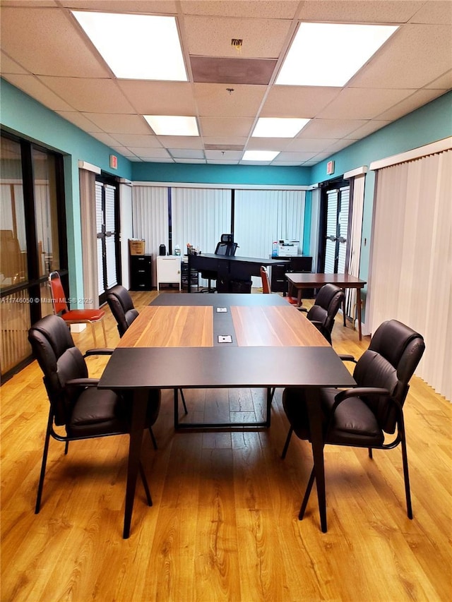 dining space featuring light wood-type flooring and a drop ceiling