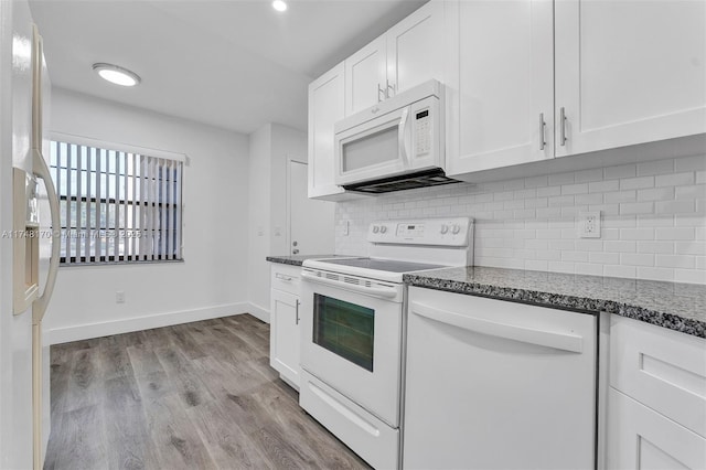 kitchen with light wood finished floors, decorative backsplash, white cabinets, white appliances, and baseboards