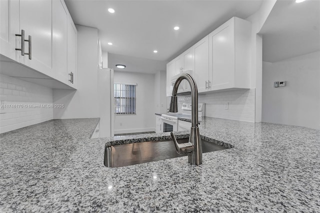 kitchen featuring white appliances, tasteful backsplash, light stone counters, and white cabinets