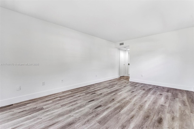 spare room with baseboards, visible vents, and light wood-style floors