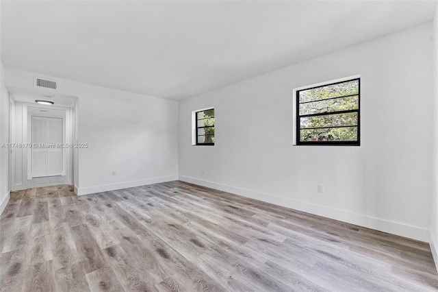 empty room featuring visible vents, light wood-style flooring, and baseboards