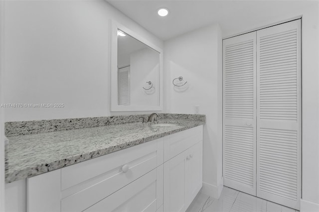 bathroom with recessed lighting, vanity, baseboards, marble finish floor, and a closet