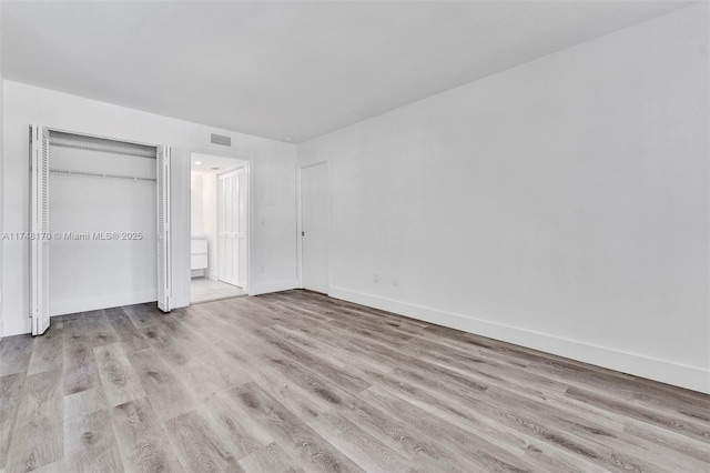 unfurnished bedroom with a closet, baseboards, visible vents, and light wood finished floors