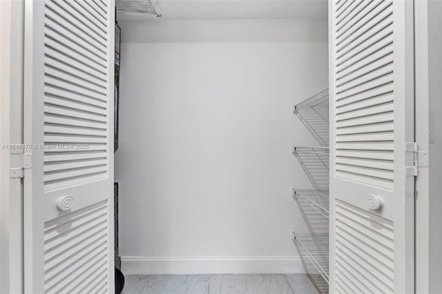 walk in closet featuring marble finish floor